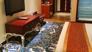 A hotel room with a TV mounted on the wall, a red desk, and a patterned carpet. - Qianhao Hotel (Tongzi County)