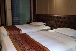 Quarto de hotel com duas camas, cabeceira estofada e porta de correr de vidro.