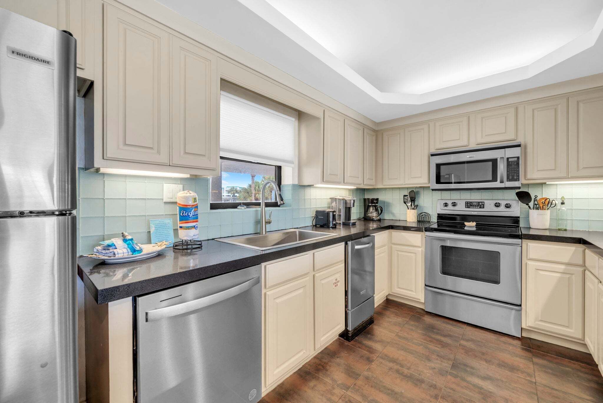 Una cocina con electrodomésticos de acero inoxidable, armarios de tonos claros y salpicadero de azulejos.