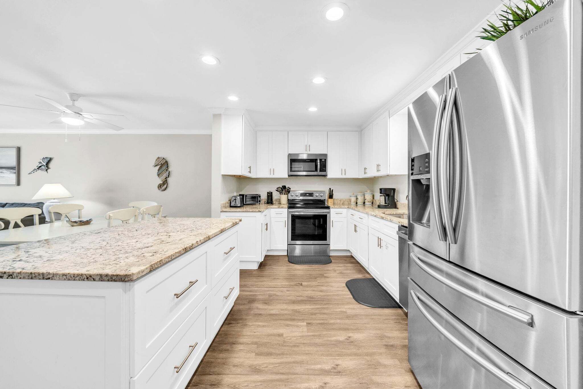 A modern kitchen with white cabinetry, stainless steel appliances, and a granite countertop.