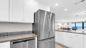 A modern kitchen with stainless steel appliances, white cabinetry, and a granite countertop.