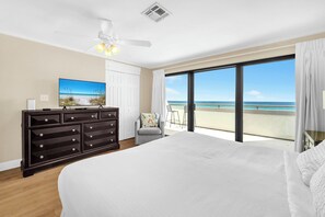 A bedroom with a large bed, a dresser, a chair, and a view of the beach. - Aegean 305: Spacious Beachfront Retreat w/ Pool and Gulf Views (Destin)