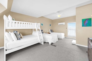 A room with bunk beds, a desk, and a window with blinds.