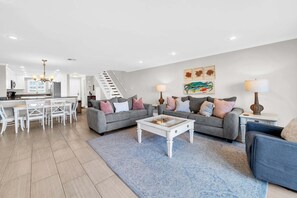 Una sala de estar moderna con un sofá gris, una mesa de centro y una escalera que lleva a un nivel superior.
