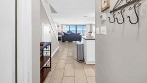Un interior moderno con una escalera, una zona de cocina y vistas a la playa.