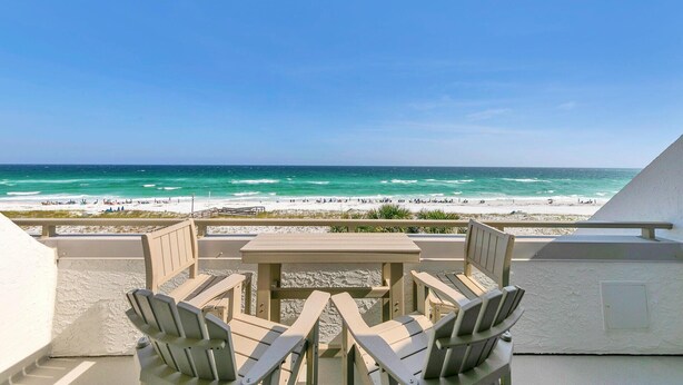A beach view from a balcony with a table and chairs, overlooking the ocean and beach. - Aegean 309: Spacious 3BR Condo with Gulf Views (Destin)