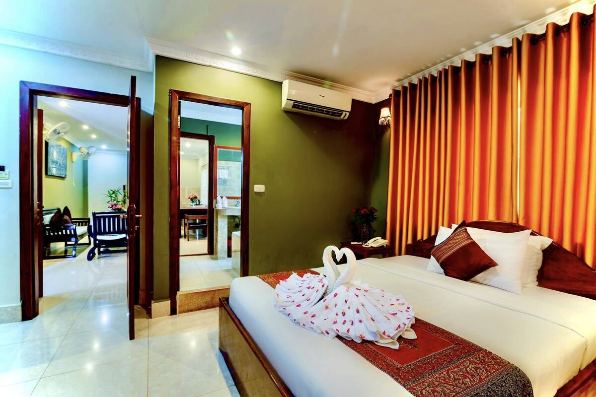 Quarto de hotel com cama, espelho, escrivaninha e cadeira.