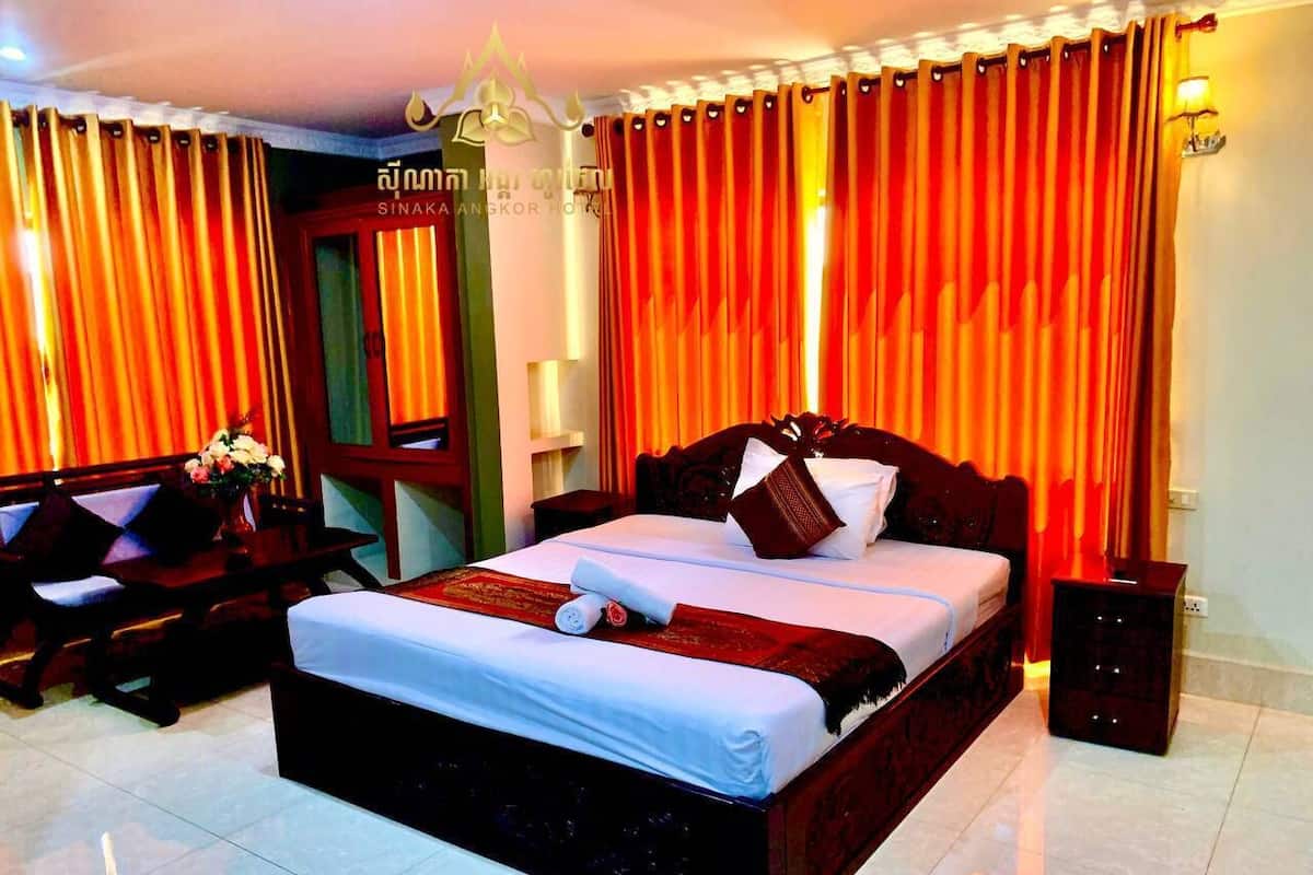 Quarto de hotel com uma cama grande, uma escrivaninha e uma cadeira.