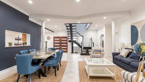 Una sala moderna con comedor, una escalera y un sofá.