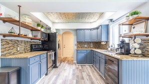 Une cuisine moderne avec des armoires bleues, un mur de fond en briques et une lucarne.