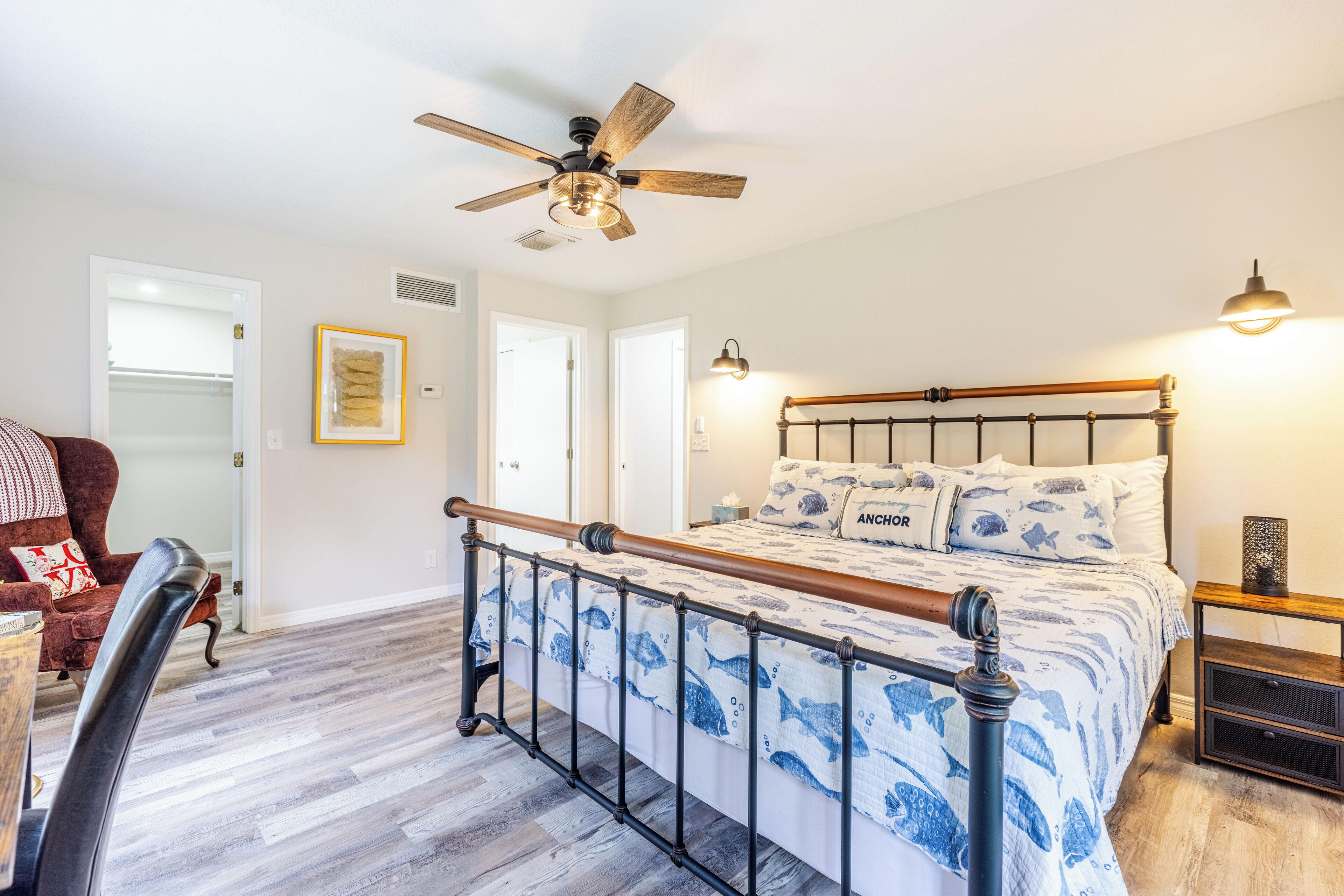 Une chambre à coucher avec un lit, un ventilateur de plafond, une table de chevet et une chaise.