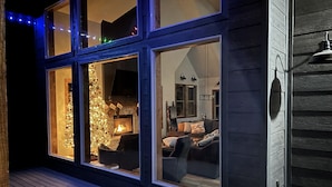 A cozy interior with a fireplace, a dining area, and a view of the deck.