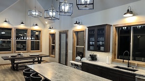 A modern kitchen with a large island, pendant lights, and wooden cabinetry.
