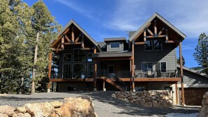 A two-story log cabin with a stone foundation, multiple balconies, and a garage.