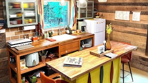 Une cuisine chaleureuse avec des murs en bois, un îlot central en bois et des luminaires suspendus.