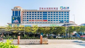 A hotel with multiple floors, a prominent sign for a casino, and a well-maintained outdoor area with trees and a fence. - Vienna International Hotel ( Shunde Jun'anBiguiyuan Golf Club） (Foshan)