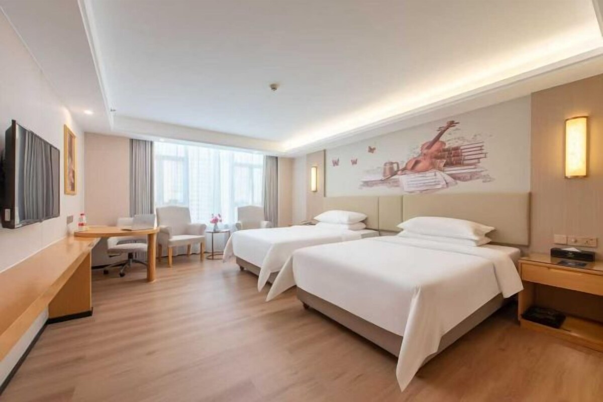 A hotel room with two beds, a desk, a chair, a TV, and a painting on the wall.