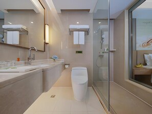 A modern bathroom with a glass shower enclosure, a toilet, and a sink with a mirror. - Vienna International Hotel ( Shunde Jun'anBiguiyuan Golf Club） (Foshan)