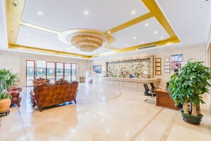 A spacious lobby with a reception desk, a large chandelier, and a view of the outdoors. - Vienna International Hotel ( Shunde Jun'anBiguiyuan Golf Club） (Foshan)