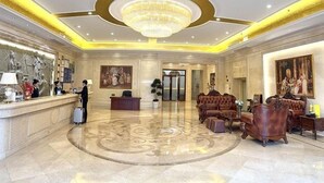 A hotel lobby with a reception desk, seating area, and a large chandelier. - Vienna International Hotel ( Shunde Jun'anBiguiyuan Golf Club） (Foshan)