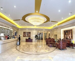 A hotel lobby with a reception desk, seating area, and a large chandelier. - Vienna International Hotel ( Shunde Jun'anBiguiyuan Golf Club） (Foshan)