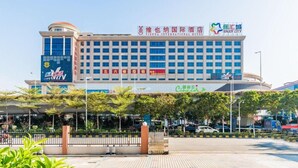 A multi-story hotel with a prominent sign for Vienna International Hotel and a large outdoor area with trees and a fence. - Vienna International Hotel ( Shunde Jun'anBiguiyuan Golf Club） (Foshan)