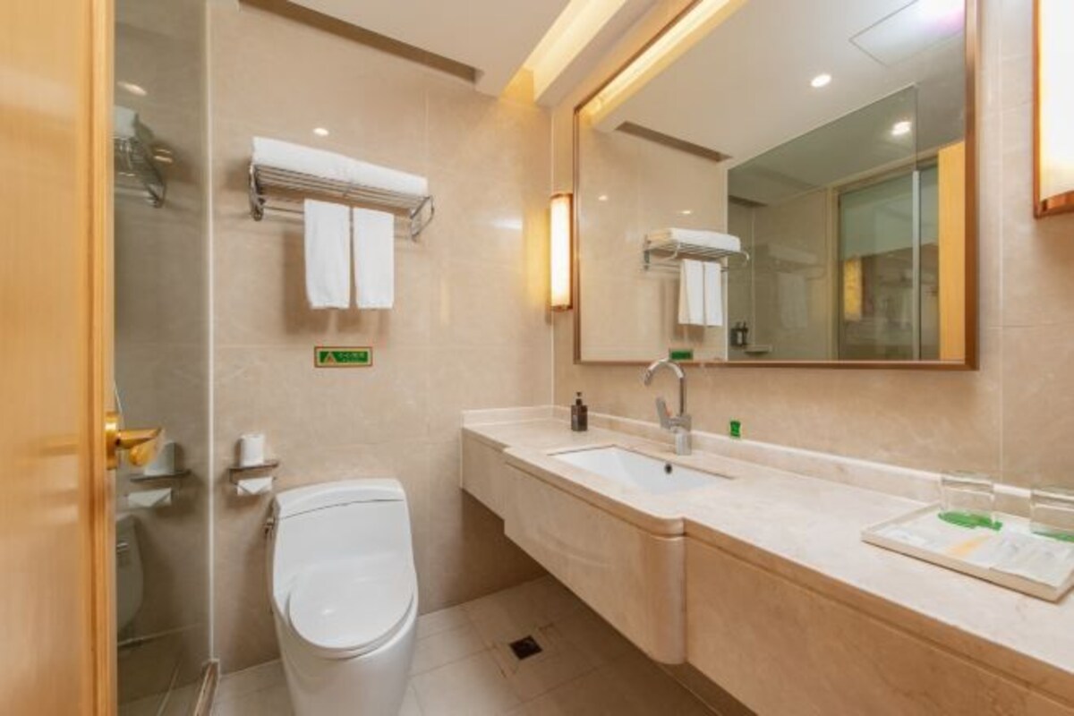 A modern bathroom with a toilet, sink, and mirror.