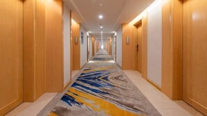 A long, narrow hotel corridor with wooden doors on both sides and a patterned carpet. - Vienna International Hotel ( Shunde Jun'anBiguiyuan Golf Club） (Foshan)