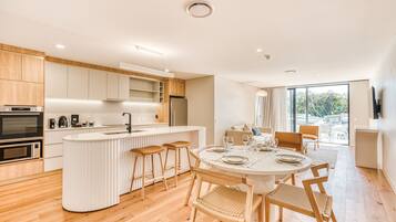 A modern kitchen with a central island, wooden flooring, and a dining area with a round table and chairs.