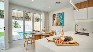 Una cocina moderna con encimera de mármol, un comedor con mesa de madera y vistas a una piscina.