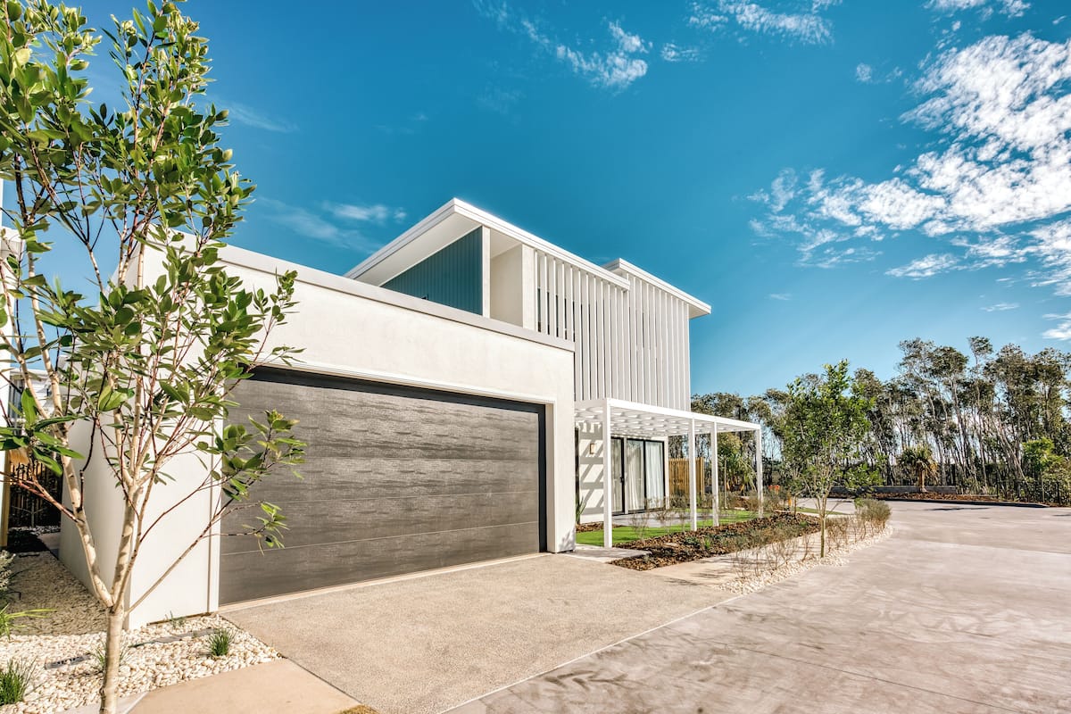 A modern two-story house with a garage, a covered patio, and a well-maintained garden.