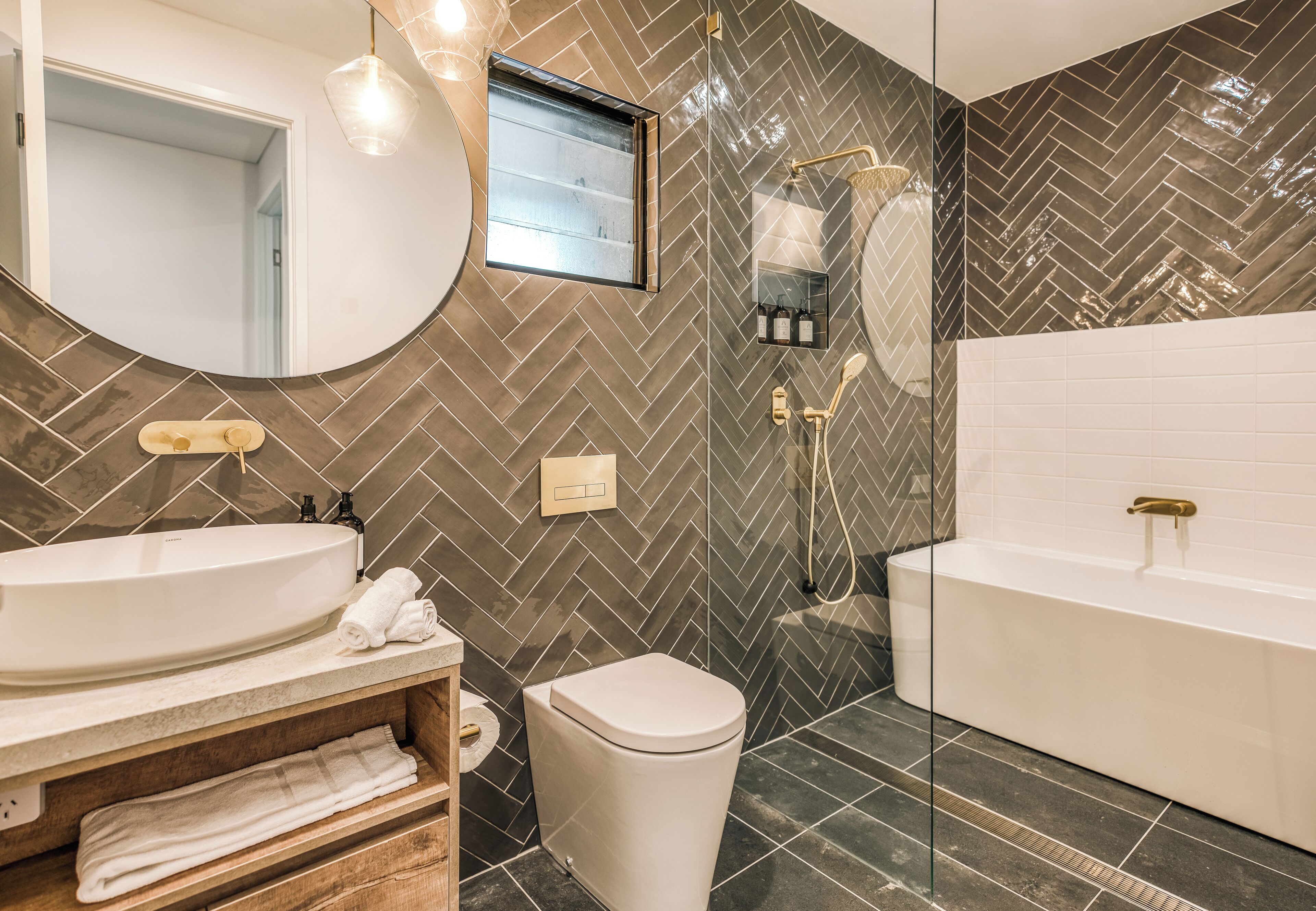 A modern bathroom with a large oval sink, a toilet, and a bathtub.