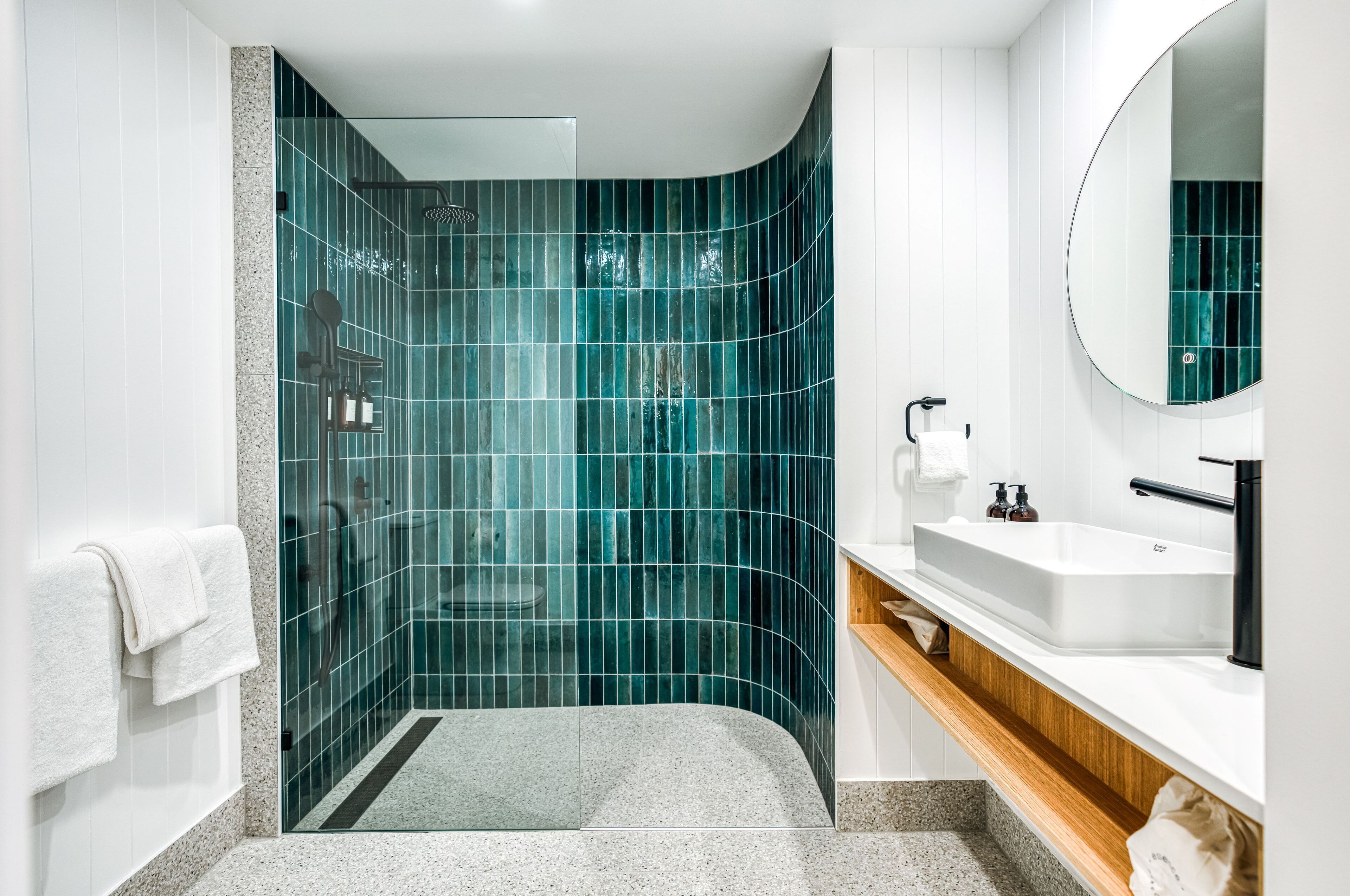 A modern bathroom with a curved shower, a white sink, and a mirror.