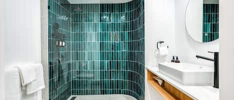 A modern bathroom with a curved shower, a white sink, and a mirror.