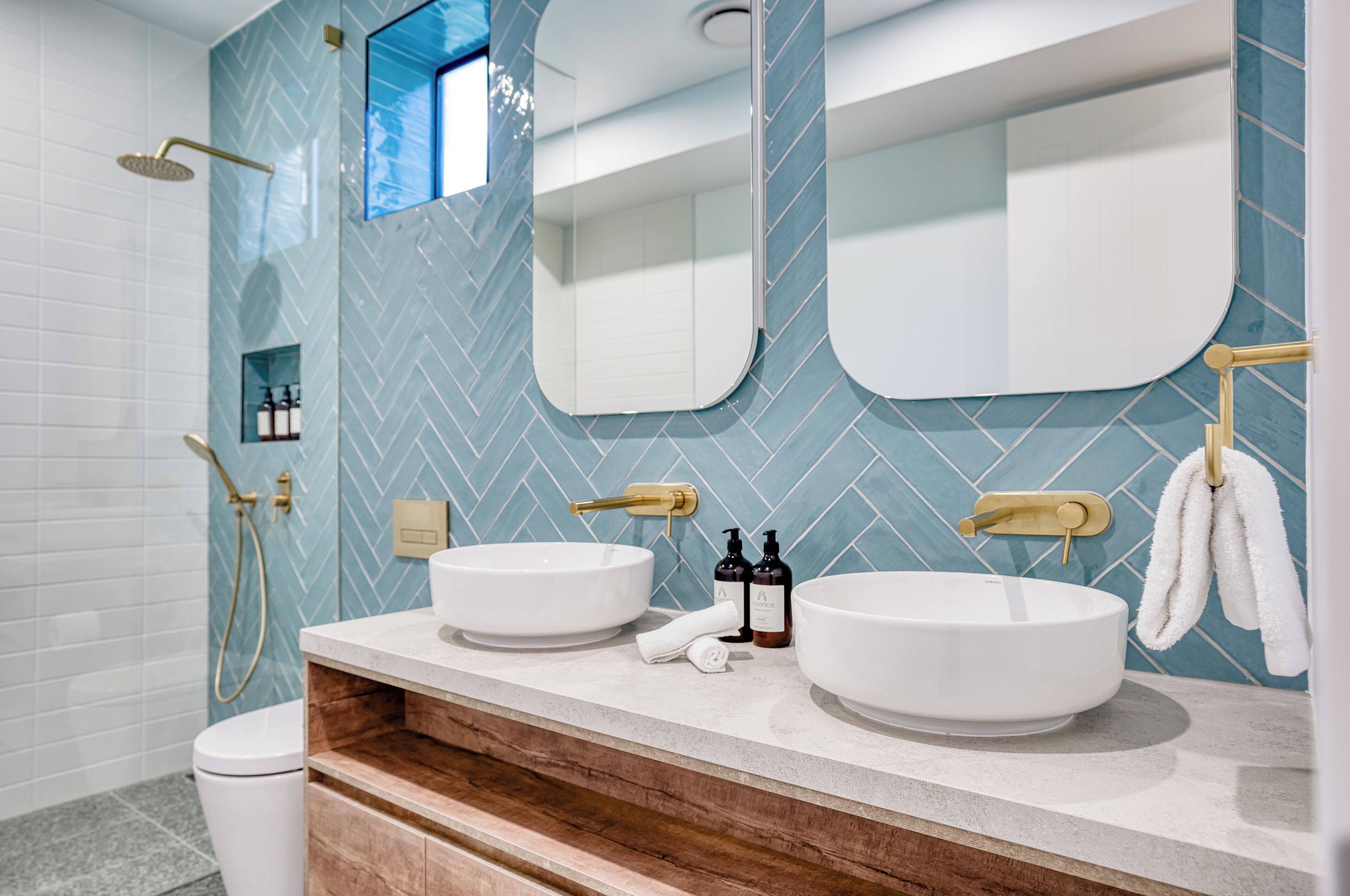 Un baño moderno con dos lavamanos, ducha y espejo.