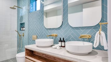 Un baño moderno con dos lavamanos, ducha y espejo.