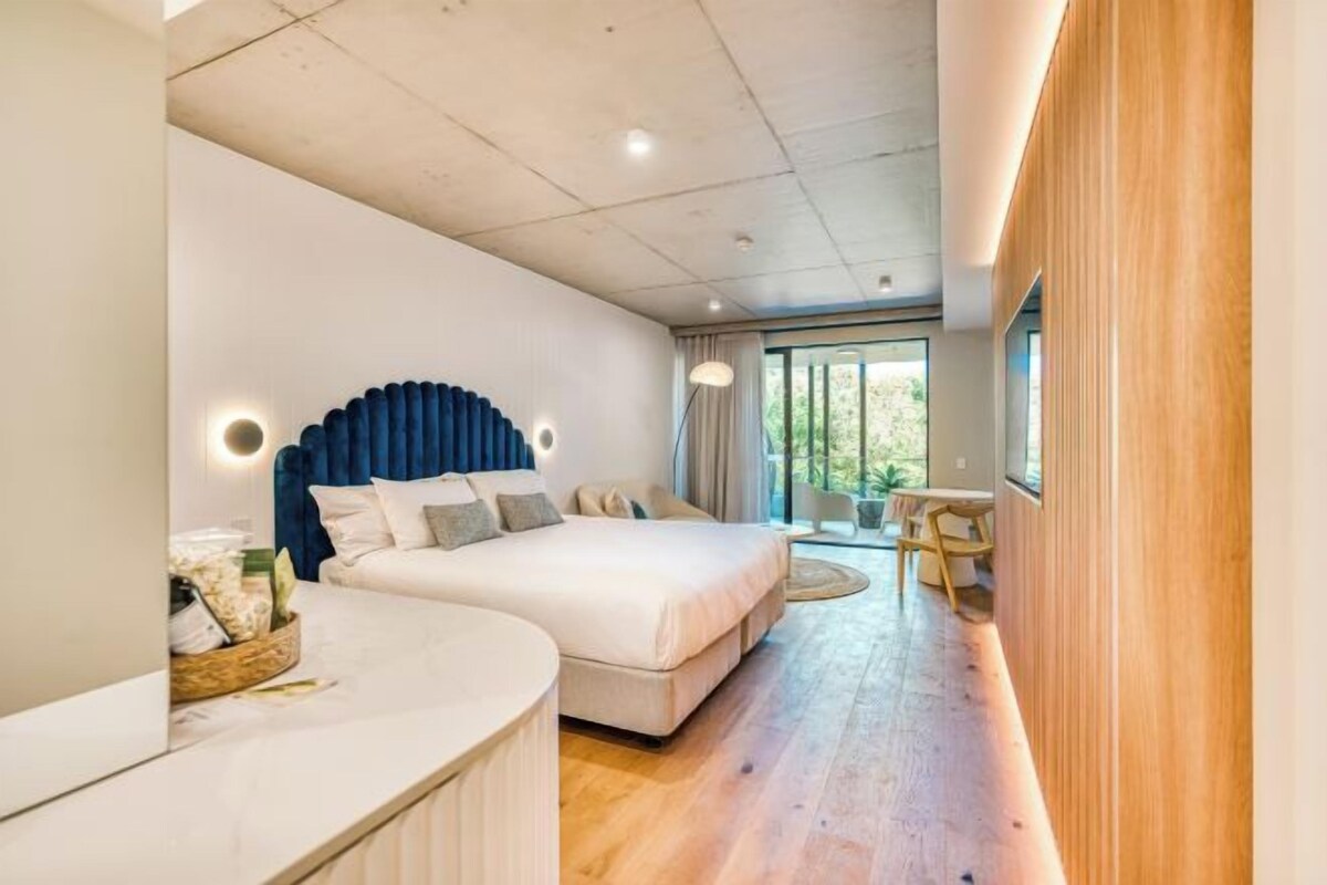 A modern bedroom with a large bed, a bedside table, and a TV mounted on the wall.
