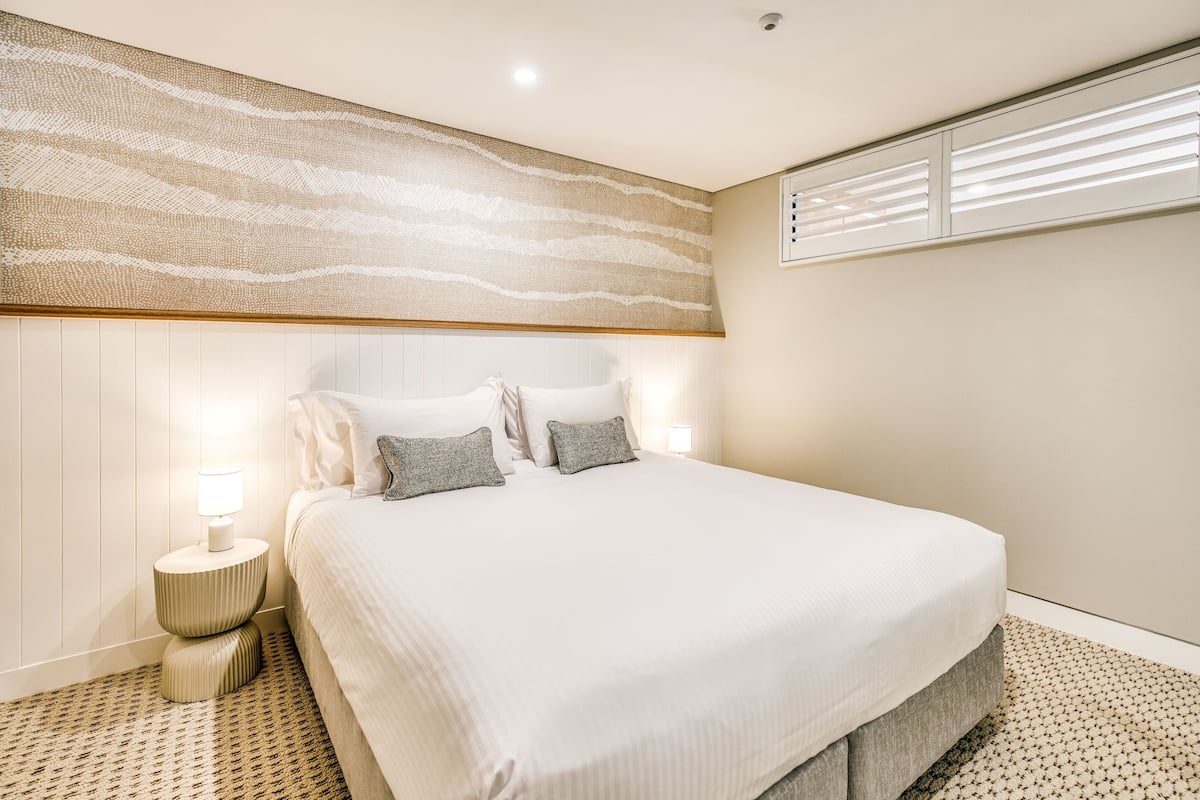 A neatly arranged bedroom with a large bed, two bedside lamps, and a patterned carpet.