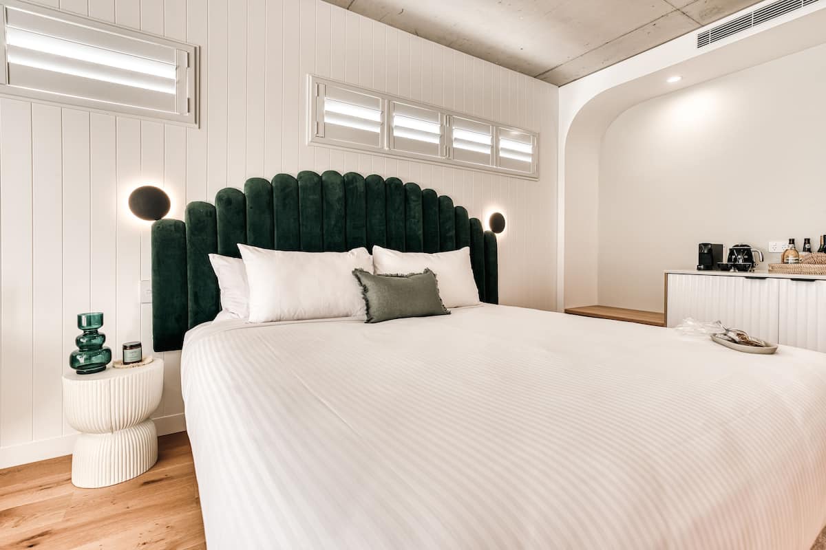 A bedroom with a large bed, a bedside table, a nightstand, a dresser, and a built-in shelf.