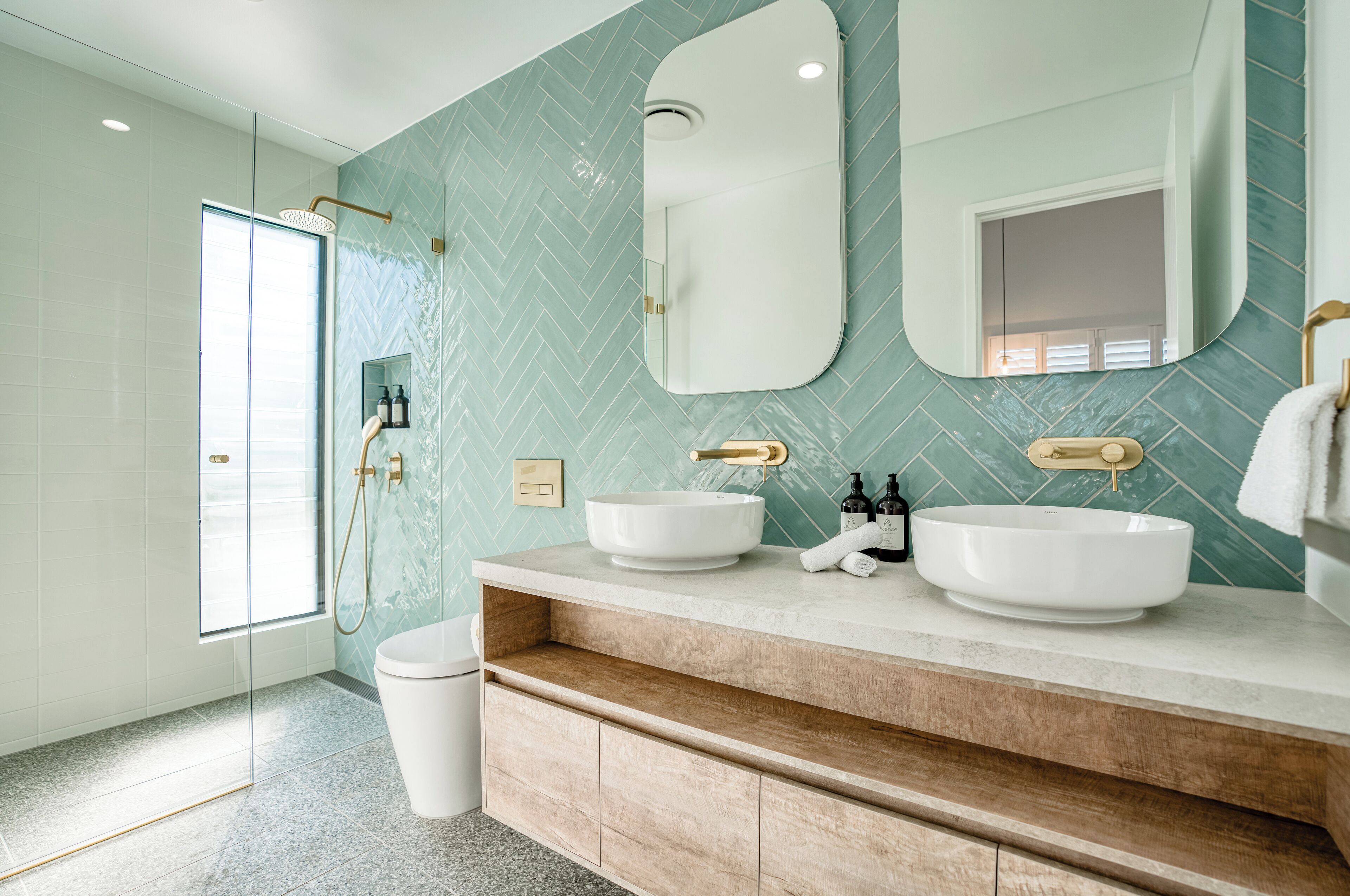 A modern bathroom with two sinks, a large mirror, and a shower.