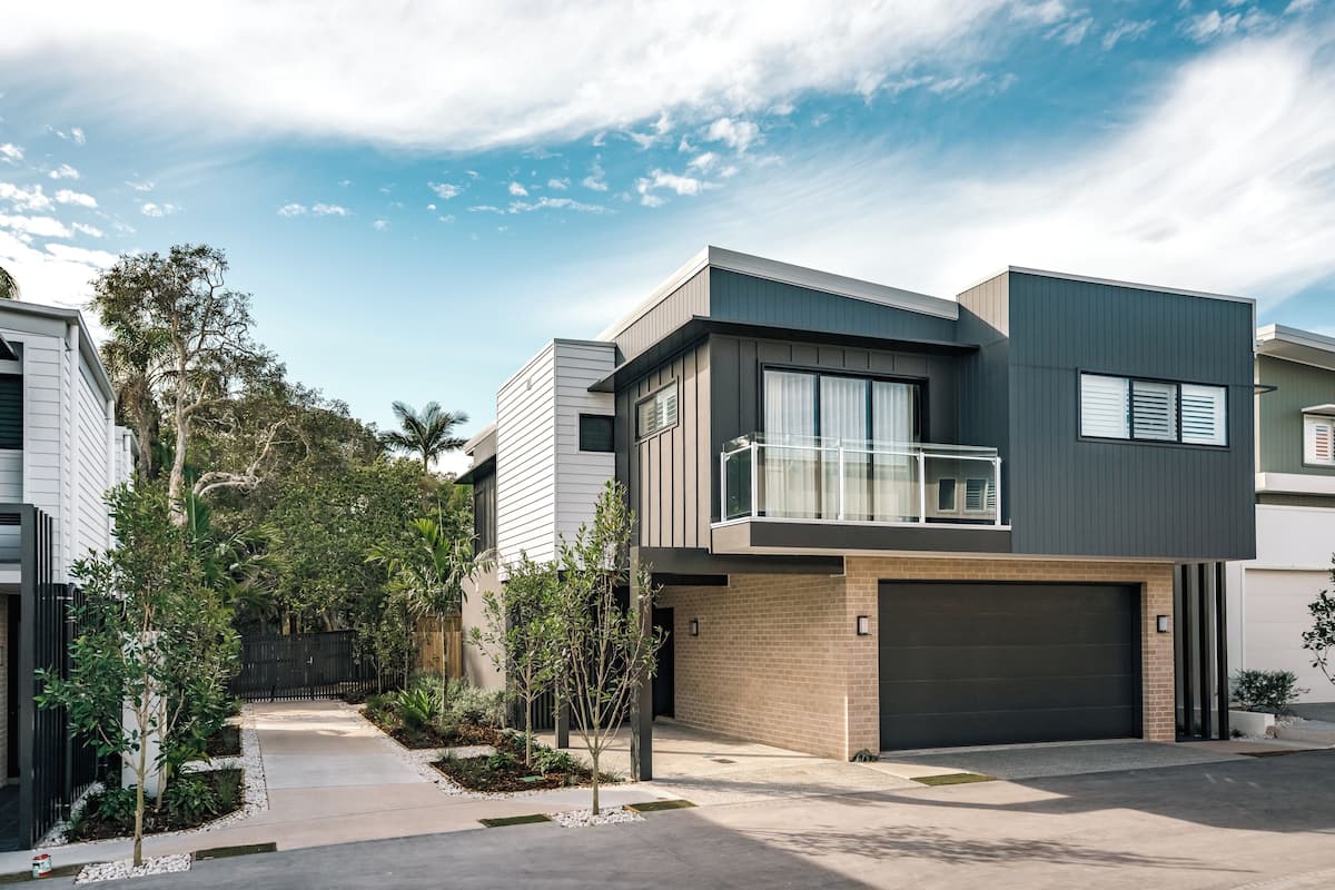 A modern two-story house with a balcony, a garage, and a well-maintained garden.