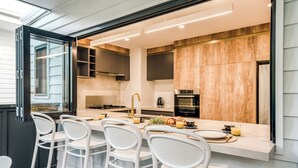 Una cocina moderna con taburetes blancos, una isla central y armarios de madera.