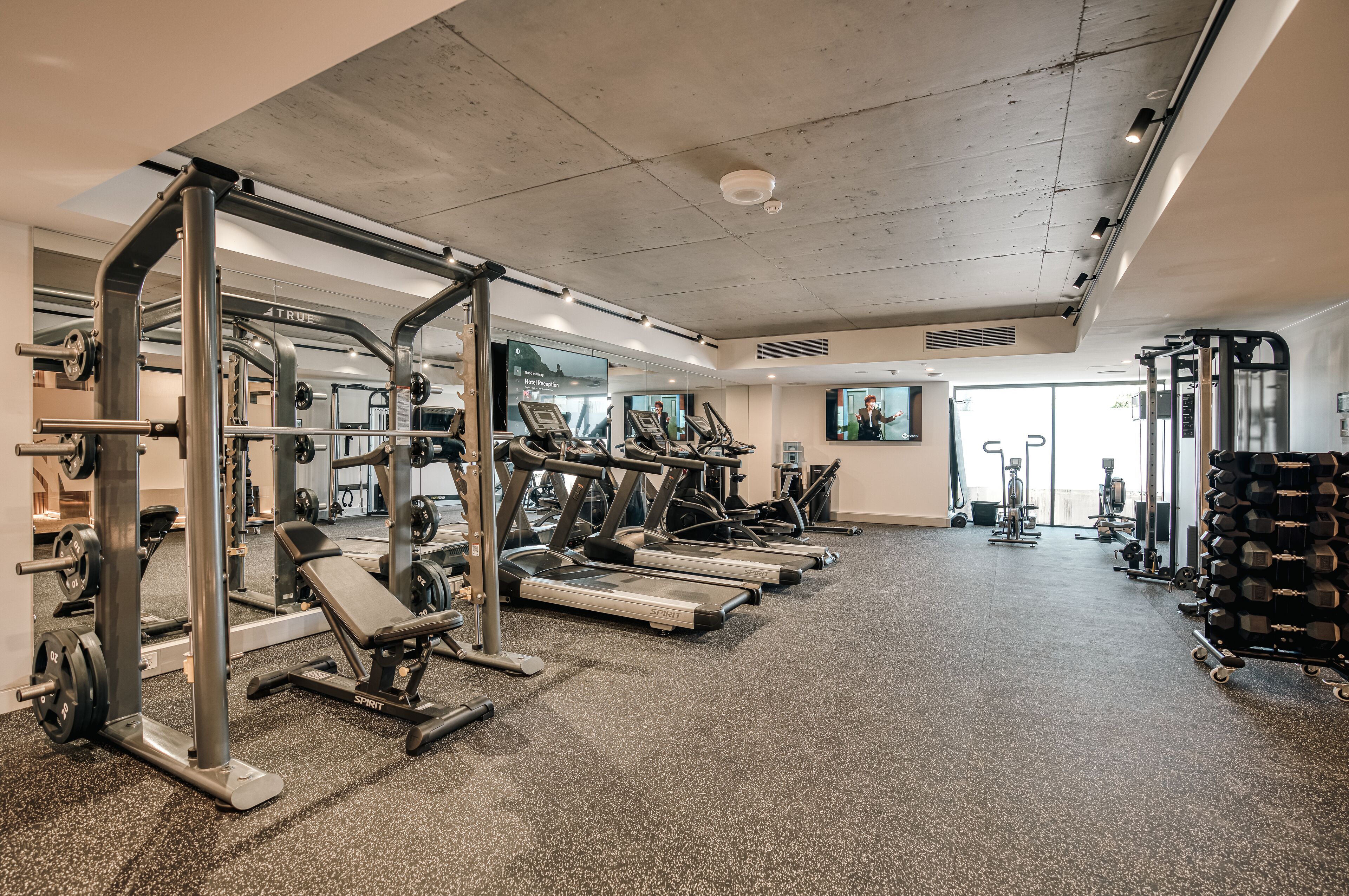 Une salle de sport équipée de tapis de course, d’appareils de musculation et de poids libres.