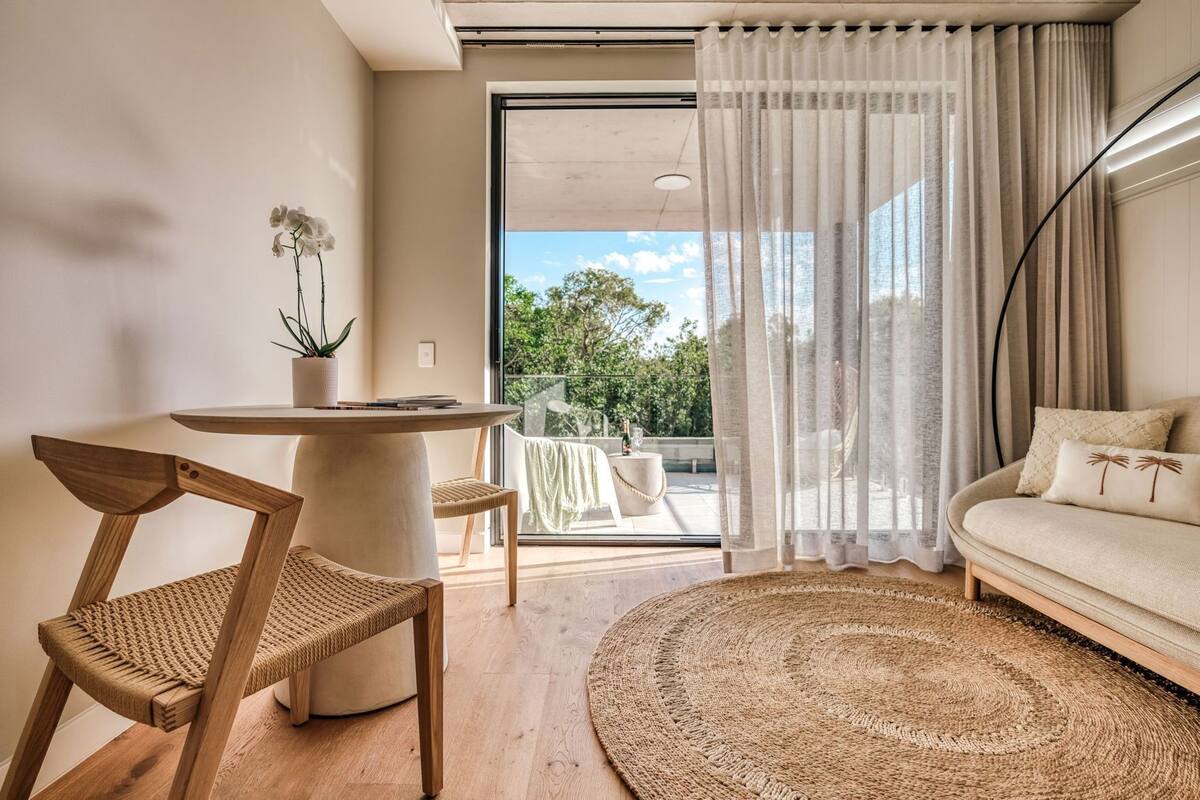 A modern living room with a round table, a sofa, a chair, and a view of the outdoors.