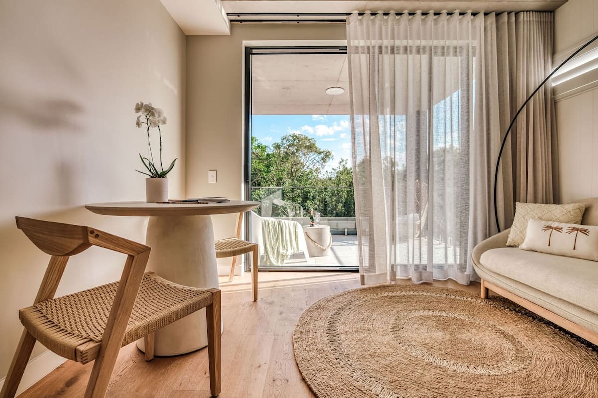 Una sala de estar moderna con una mesa redonda, un sofá, un sillón y vistas al exterior.