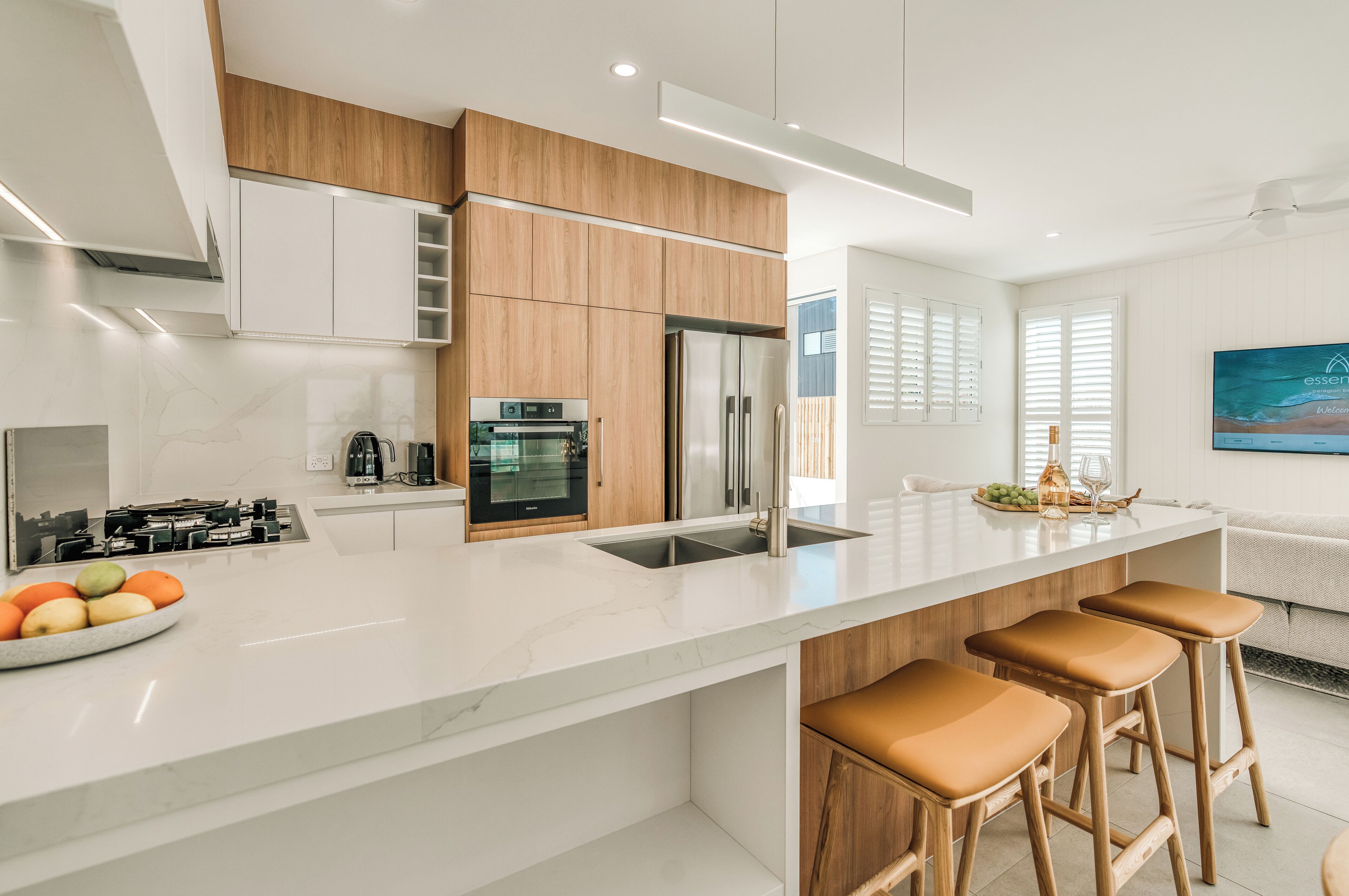 A modern kitchen with white cabinetry, a stainless steel refrigerator, and a marble countertop.