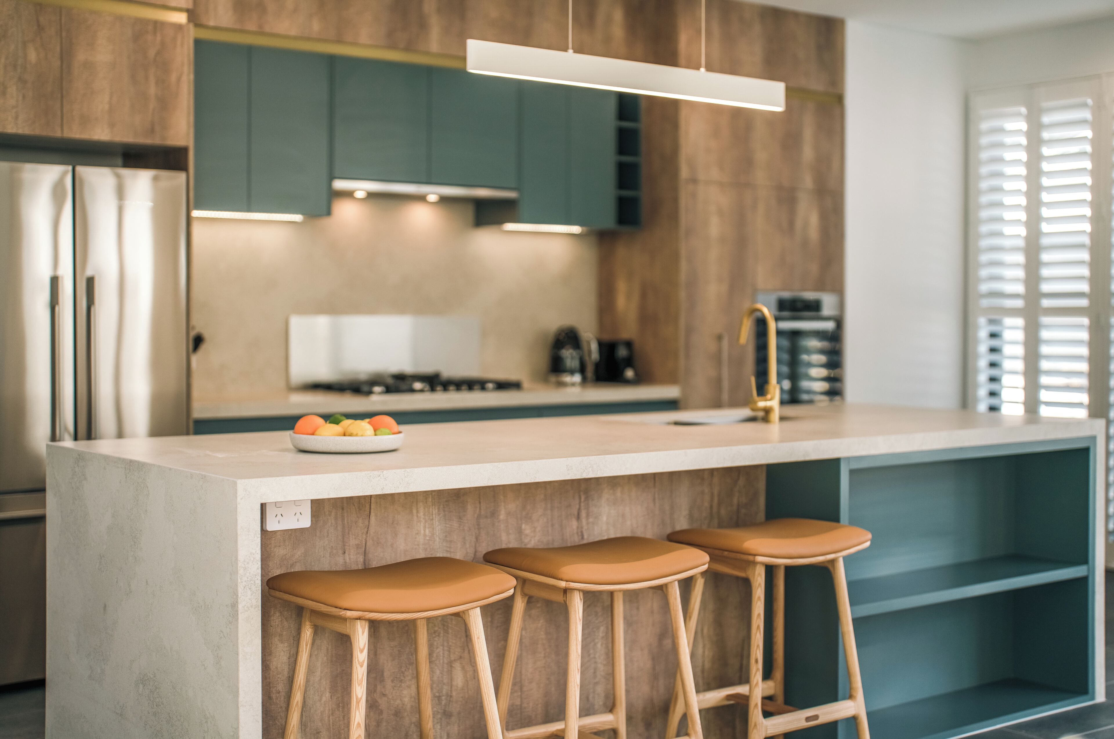 A modern kitchen with a central island, bar stools, and a built-in oven.