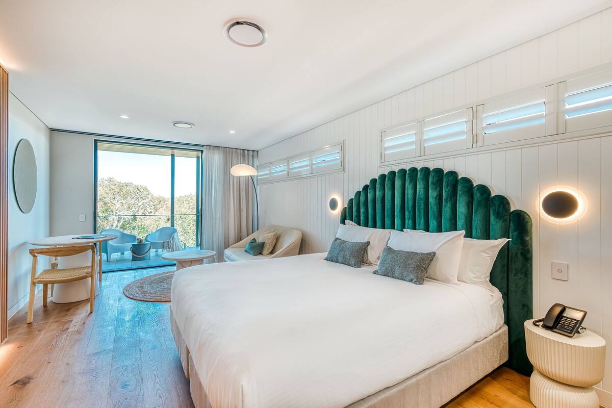 A modern bedroom with a large bed, a desk, and a chair.