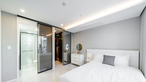 Une chambre moderne avec un grand lit, une table de chevet, un miroir et une armoire.