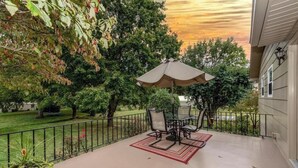 A covered patio with a table and chairs, surrounded by a metal railing and trees. - Discover Maryville and the Great Smoky Mountains (Maryville)